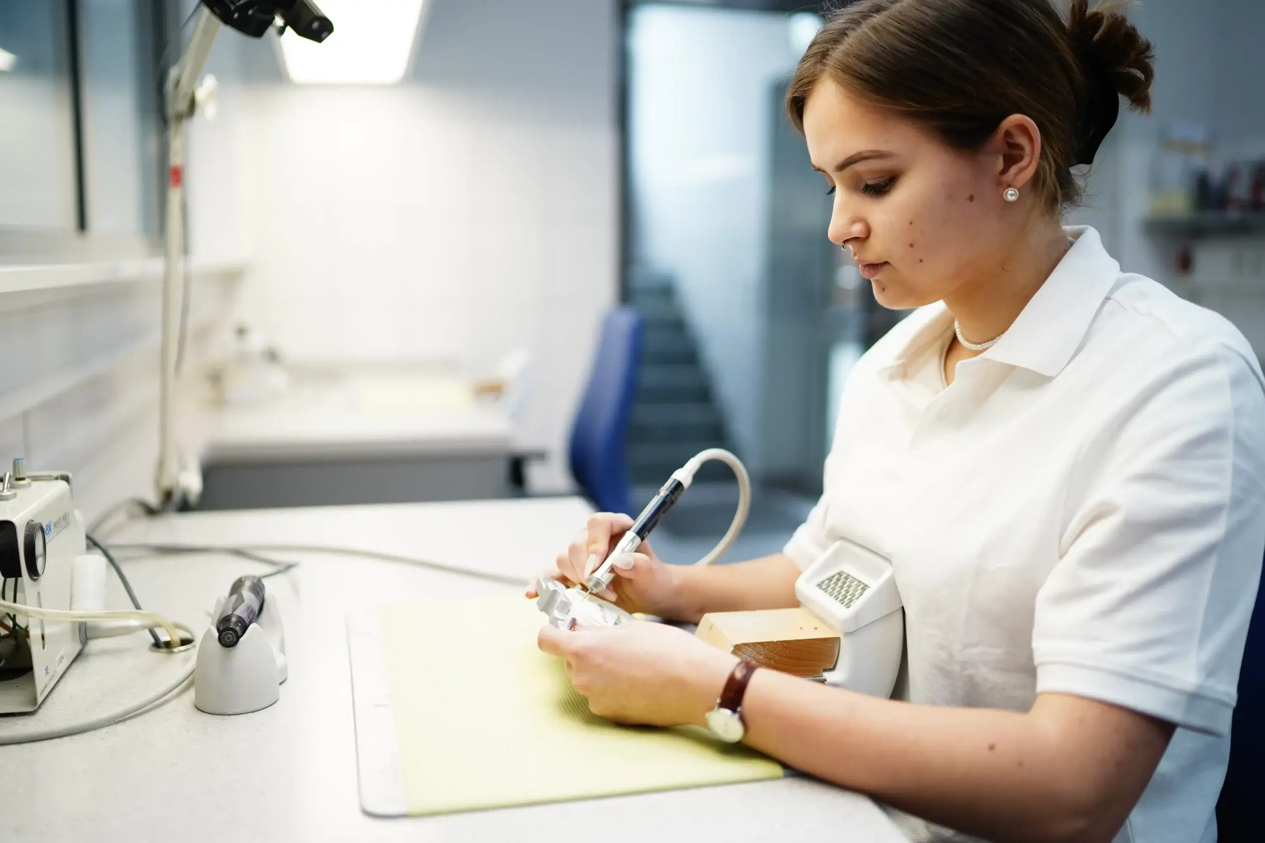 Präzisionshandwerk im Dentallabor Voigt Dental: Individuelle Anpassung von hochwertigen Zahnprothesen Material durch eine Fachkraft, was die Zahntechniker Aufgaben suggerieren.